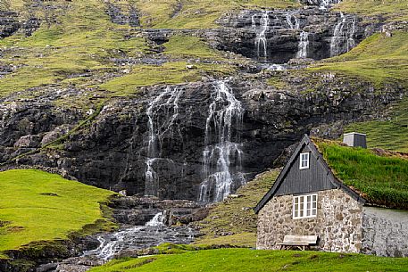 A turf covered house in front of a waterfall in Saksun village on Streymoy island, Faeroe islands, Denmark, Europe